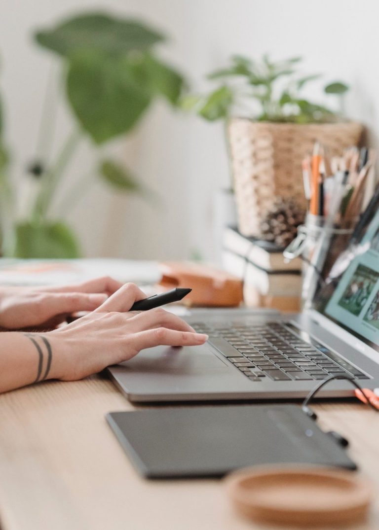 Un cadre externalisé en train de travailler sur son ordinateur une personne en train de travailler. En arriere plan du bureau des stylos dans un pot et des plantes.
